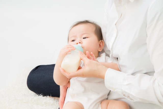 赤ちゃんにミルクをあげている女性の写真